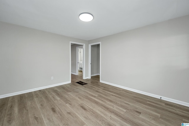 spare room with baseboards and wood finished floors