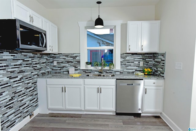 kitchen with backsplash, dark hardwood / wood-style flooring, white cabinetry, appliances with stainless steel finishes, and sink