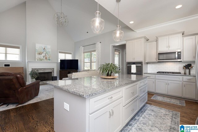 kitchen featuring appliances with stainless steel finishes, hanging light fixtures, white cabinetry, dark hardwood / wood-style flooring, and a center island