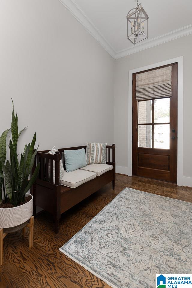 entrance foyer with an inviting chandelier, ornamental molding, and dark wood-type flooring