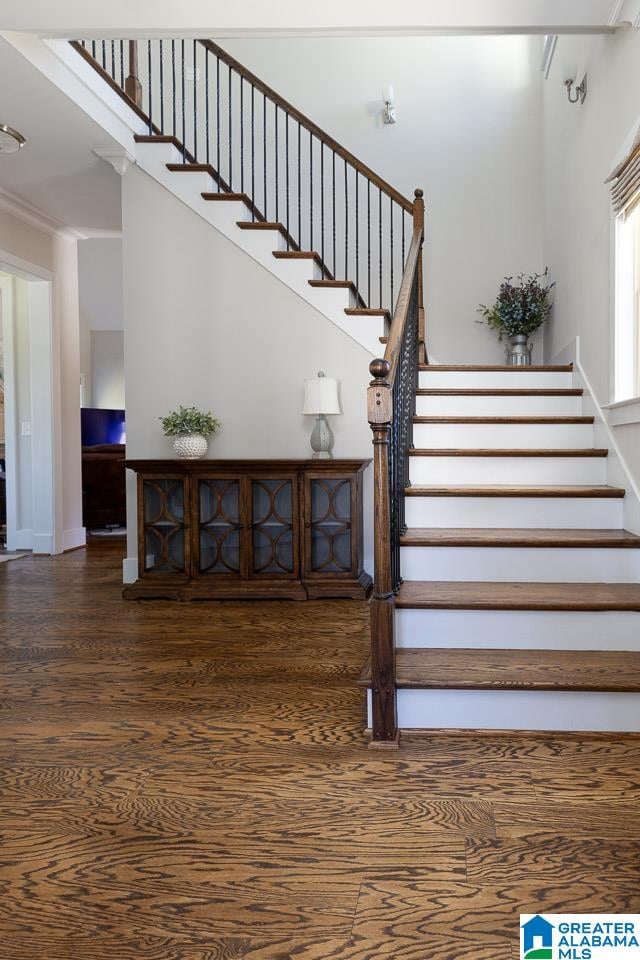 staircase with ornamental molding, hardwood / wood-style floors, and a high ceiling