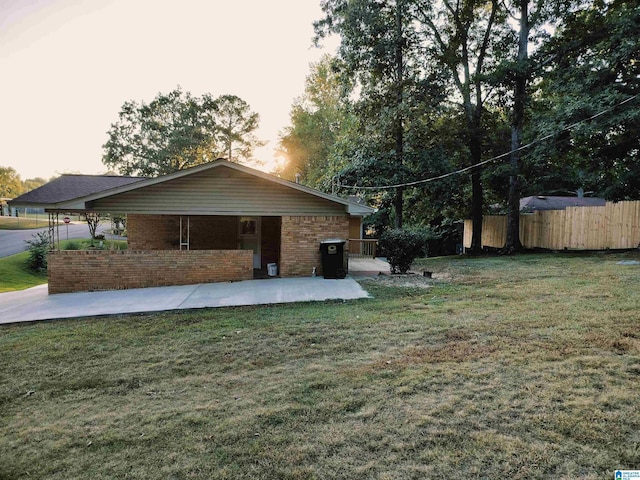 exterior space featuring a patio area, fence, a lawn, and brick siding