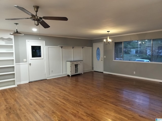 unfurnished living room with dark wood-type flooring, crown molding, baseboards, and ceiling fan with notable chandelier