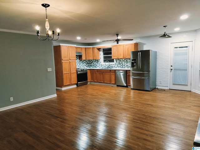 kitchen with appliances with stainless steel finishes, a sink, light countertops, pendant lighting, and backsplash