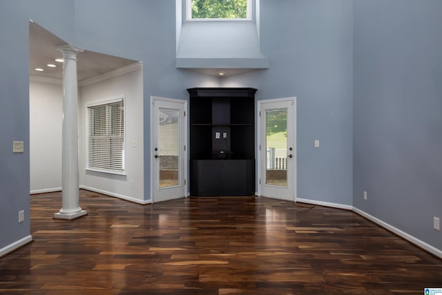 entrance foyer featuring a high ceiling, dark hardwood / wood-style floors, crown molding, and ornate columns