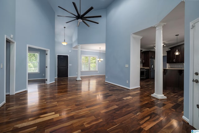 unfurnished living room featuring dark wood-type flooring, high vaulted ceiling, and ornate columns