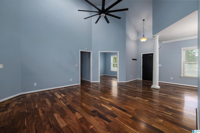 unfurnished living room with dark wood-type flooring, high vaulted ceiling, decorative columns, and a healthy amount of sunlight