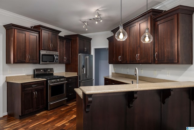 kitchen featuring hanging light fixtures, appliances with stainless steel finishes, dark hardwood / wood-style flooring, track lighting, and a breakfast bar