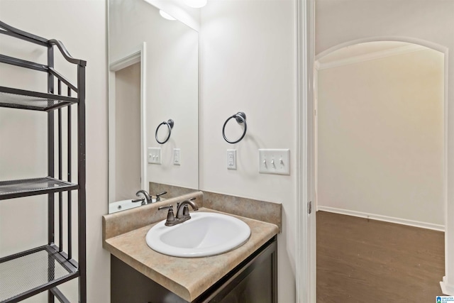 bathroom with crown molding, vanity, and hardwood / wood-style floors