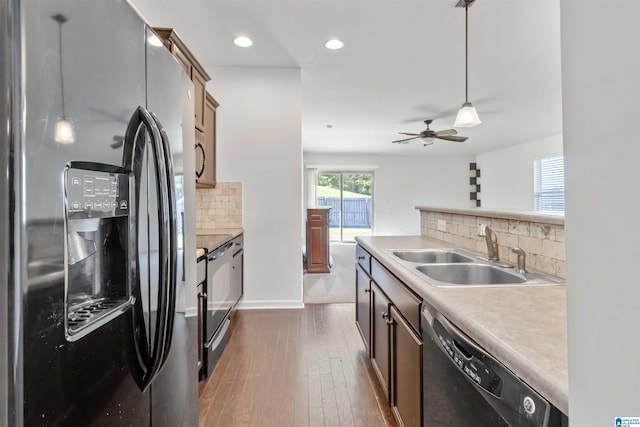 kitchen featuring dark hardwood / wood-style flooring, pendant lighting, black appliances, decorative backsplash, and ceiling fan