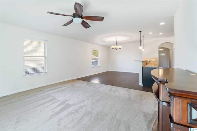 interior space with dark carpet, ceiling fan with notable chandelier, and a wealth of natural light