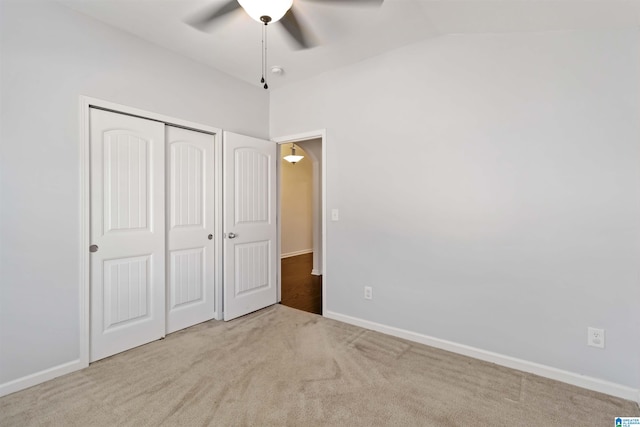 unfurnished bedroom with lofted ceiling, light colored carpet, ceiling fan, and a closet