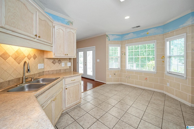 kitchen featuring a healthy amount of sunlight, ornamental molding, sink, and light hardwood / wood-style floors