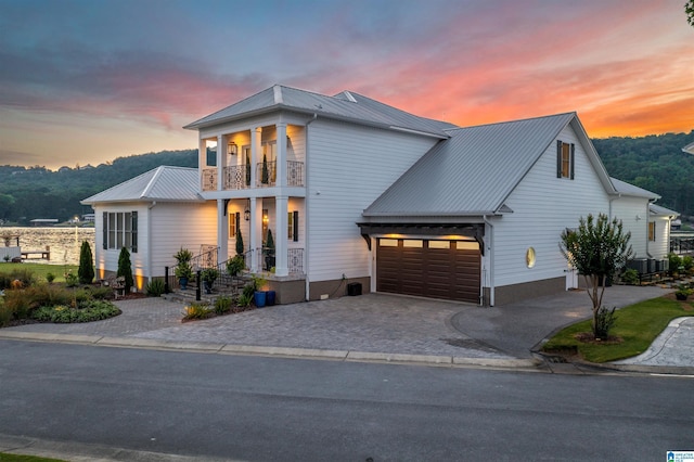 view of front of property with a garage, metal roof, decorative driveway, and a balcony