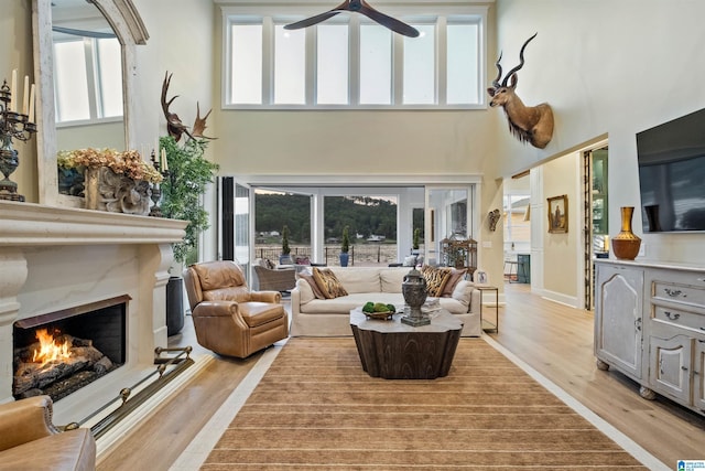 living room with a high ceiling, a premium fireplace, and light wood-style floors