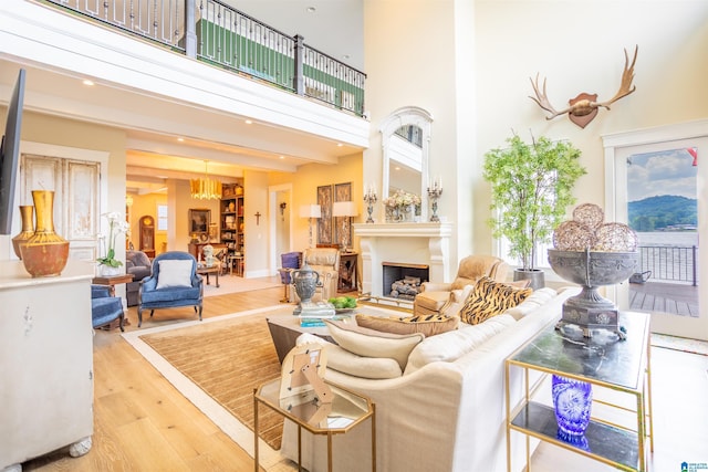 living room featuring a towering ceiling, light wood-style floors, and a fireplace