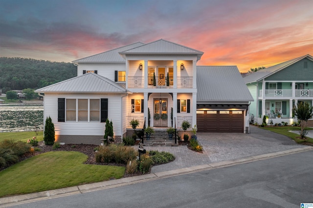 view of front facade featuring a garage, driveway, metal roof, and a balcony