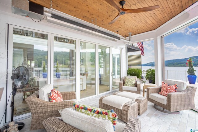 sunroom with ceiling fan, wooden ceiling, and a mountain view