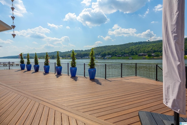 wooden deck with a water and mountain view and a view of trees