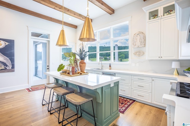 kitchen featuring light countertops, glass insert cabinets, white cabinetry, a kitchen island, and a sink