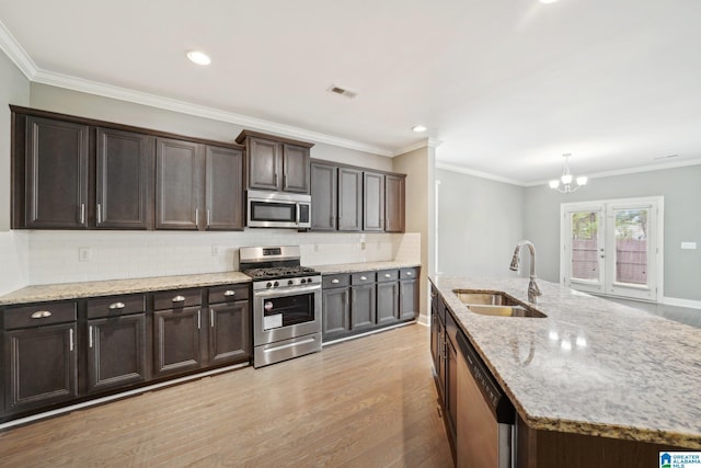 kitchen with visible vents, light wood-type flooring, a sink, tasteful backsplash, and appliances with stainless steel finishes