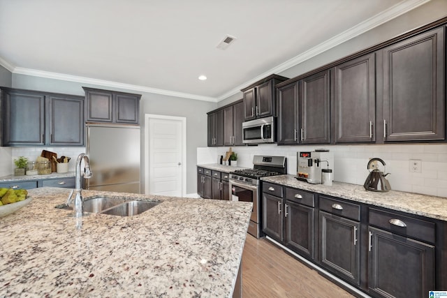 kitchen with visible vents, light wood-style flooring, ornamental molding, a sink, and appliances with stainless steel finishes