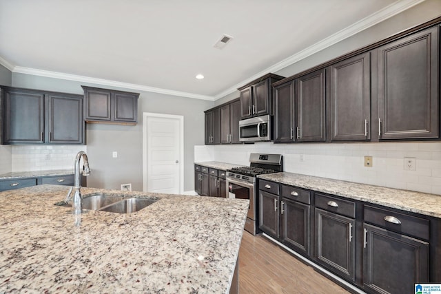 kitchen with visible vents, a sink, stainless steel appliances, light wood finished floors, and light stone countertops