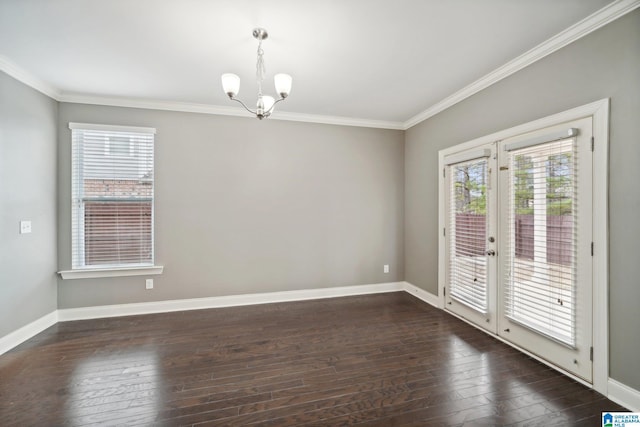 spare room with ornamental molding, an inviting chandelier, baseboards, and dark wood-style flooring