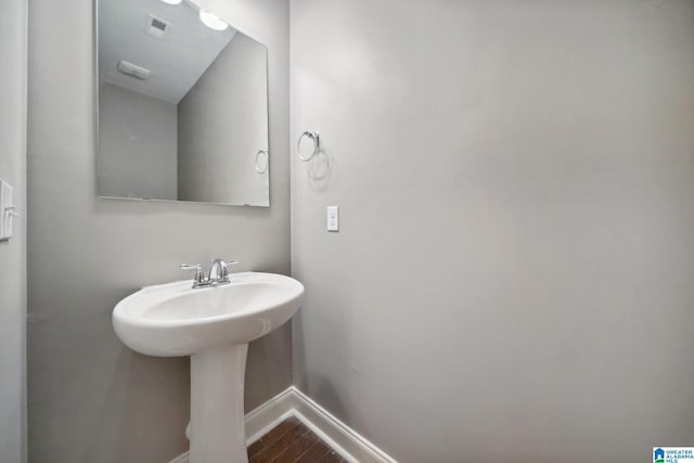 bathroom featuring visible vents, wood finished floors, baseboards, and a sink