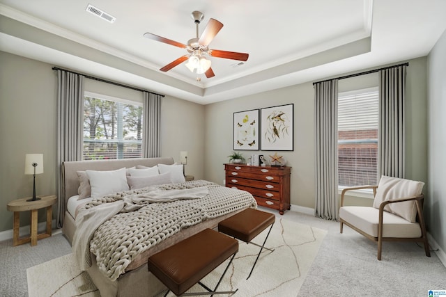 bedroom featuring visible vents, light colored carpet, baseboards, and a tray ceiling