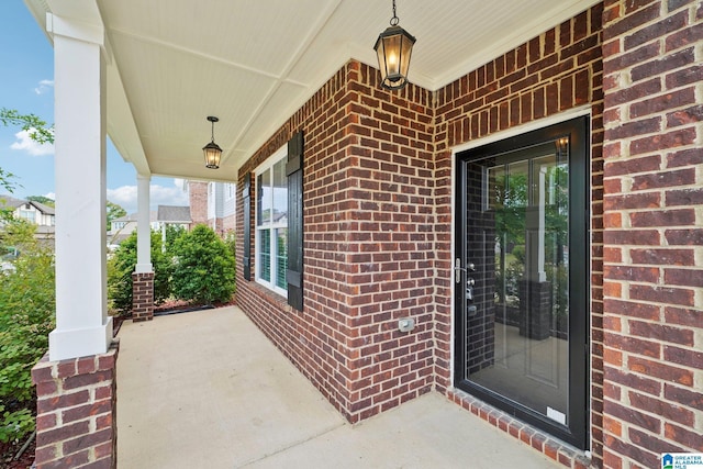 view of exterior entry with brick siding and covered porch