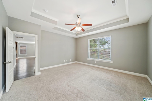 unfurnished bedroom featuring visible vents, crown molding, baseboards, carpet, and a tray ceiling