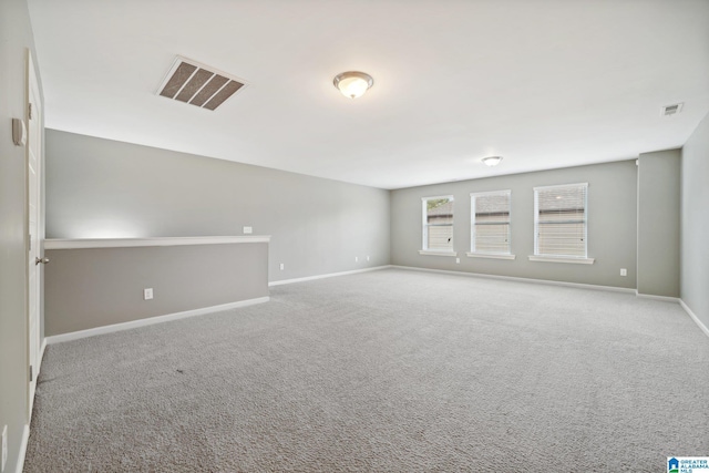 carpeted spare room with visible vents and baseboards