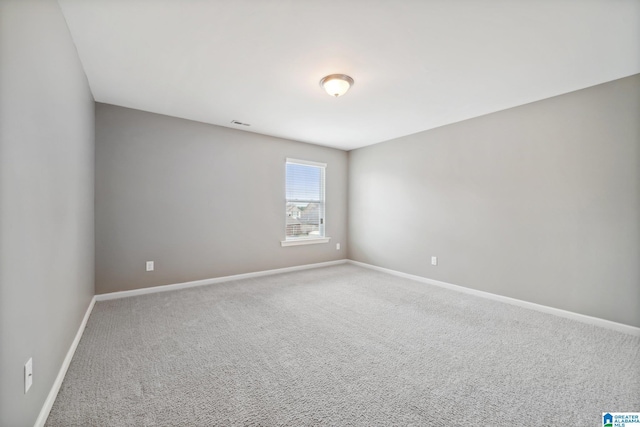 carpeted spare room featuring visible vents and baseboards