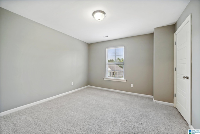 empty room featuring light carpet and baseboards