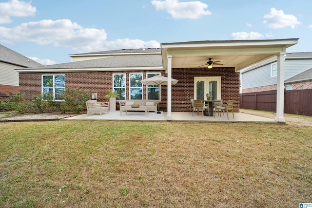 rear view of house with brick siding, ceiling fan, fence, a yard, and a patio area