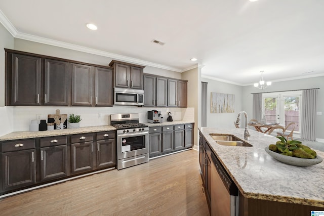 kitchen featuring visible vents, light wood-style flooring, a sink, tasteful backsplash, and appliances with stainless steel finishes