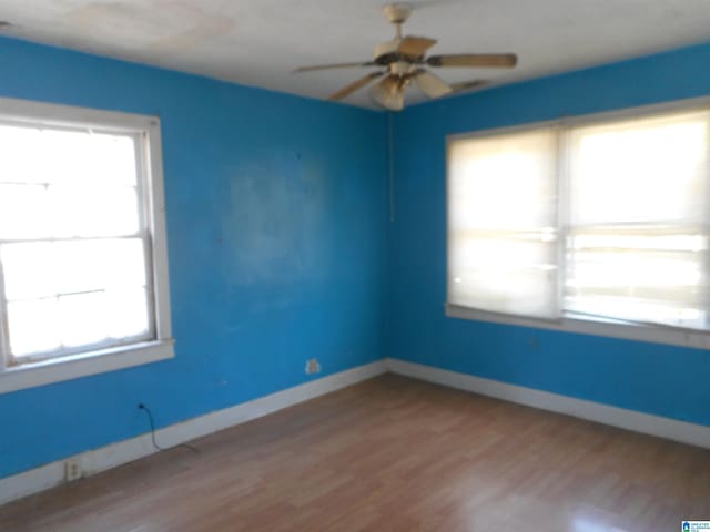 spare room with baseboards, wood finished floors, and a healthy amount of sunlight