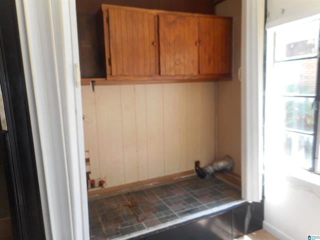 interior space with brick floor, cabinet space, and wood walls