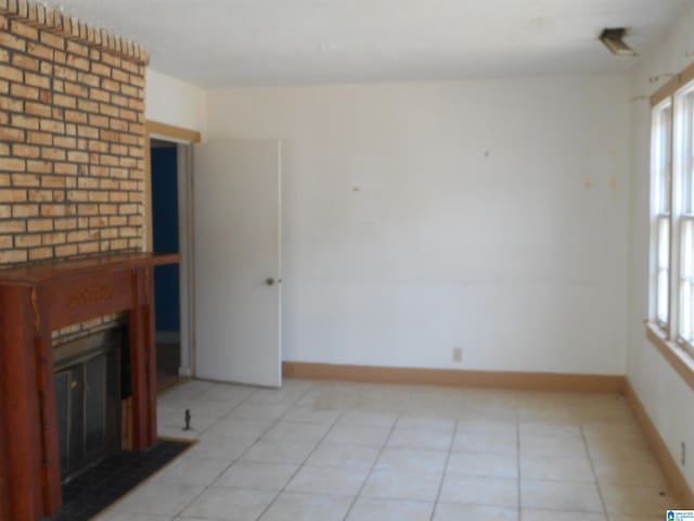 unfurnished living room with a brick fireplace and light tile patterned floors