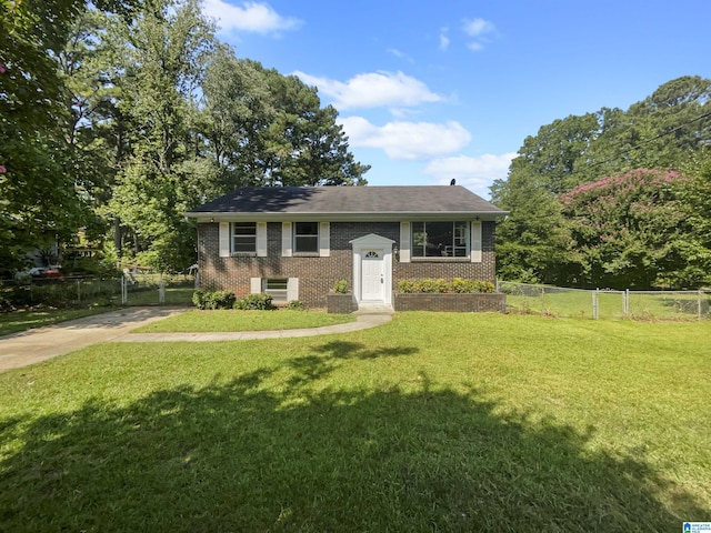 raised ranch with brick siding, fence, and a front lawn