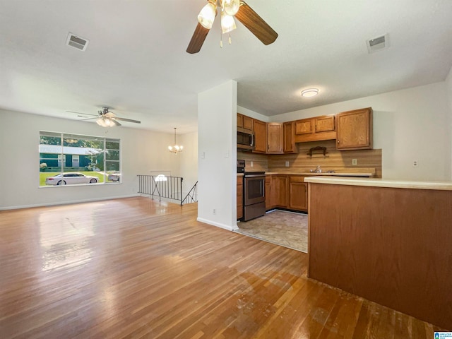 kitchen featuring ceiling fan with notable chandelier, tasteful backsplash, stainless steel appliances, kitchen peninsula, and light tile patterned flooring