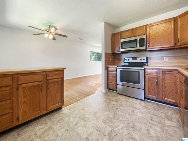 kitchen with light tile patterned floors, stainless steel appliances, ceiling fan, and decorative backsplash