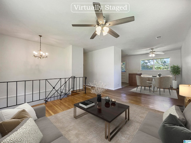 living room with ceiling fan with notable chandelier and light wood-type flooring