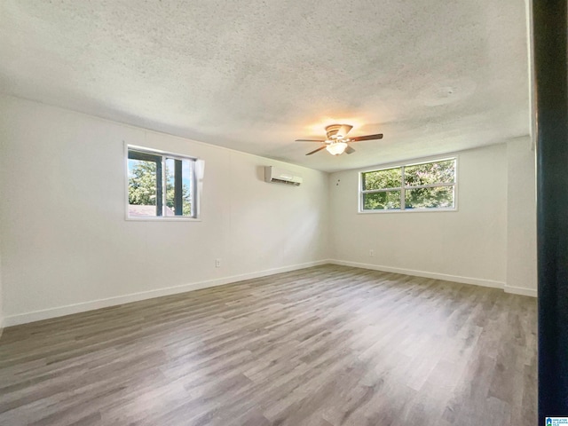 unfurnished room with a textured ceiling, a healthy amount of sunlight, hardwood / wood-style floors, and ceiling fan