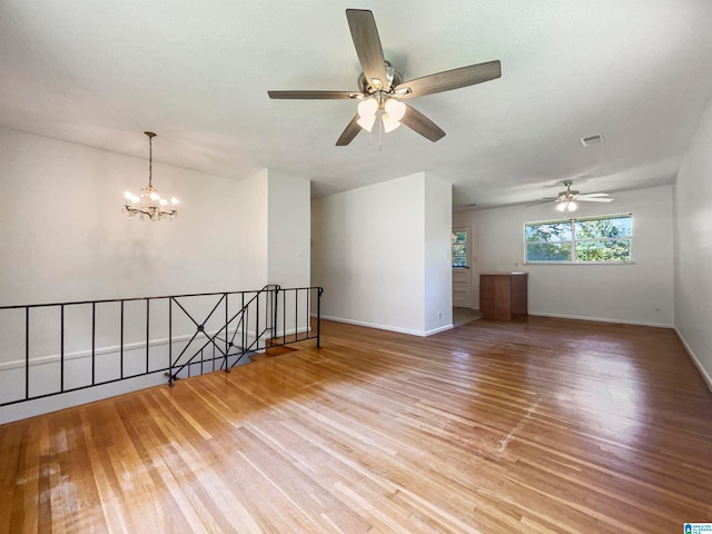 spare room with light hardwood / wood-style flooring and ceiling fan with notable chandelier