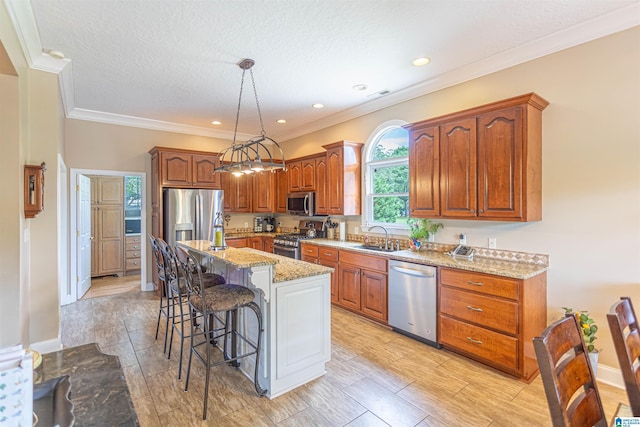 kitchen with a kitchen island, light stone counters, appliances with stainless steel finishes, pendant lighting, and a sink