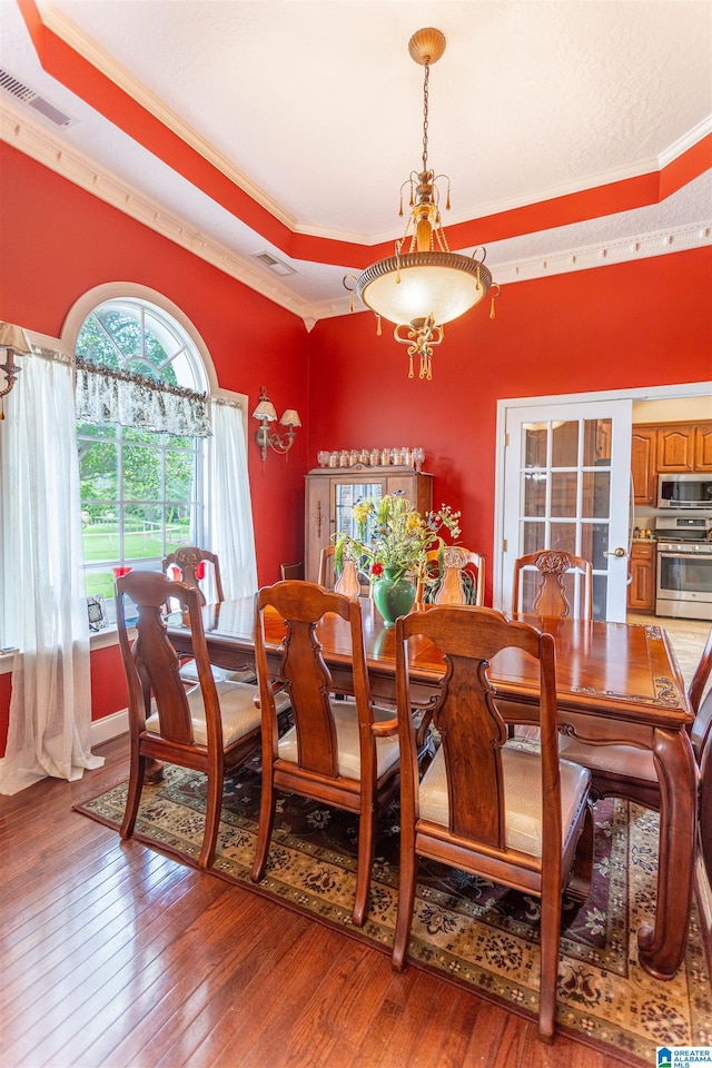 dining space with wood-type flooring, visible vents, and crown molding