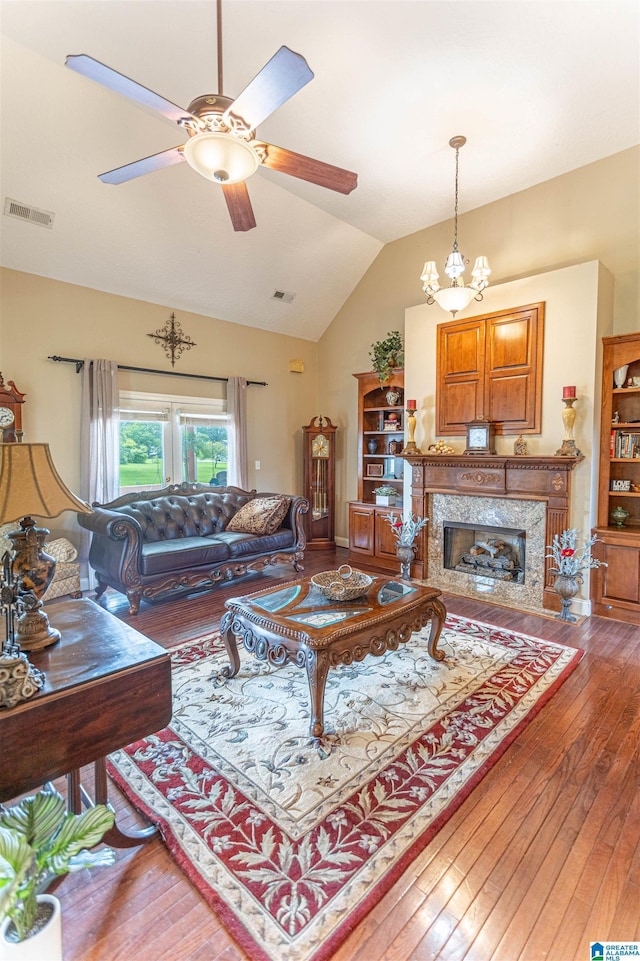 living area with a high end fireplace, wood-type flooring, visible vents, and lofted ceiling