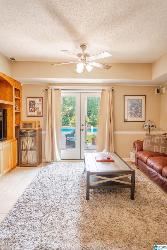 living room featuring ceiling fan, a textured ceiling, and french doors